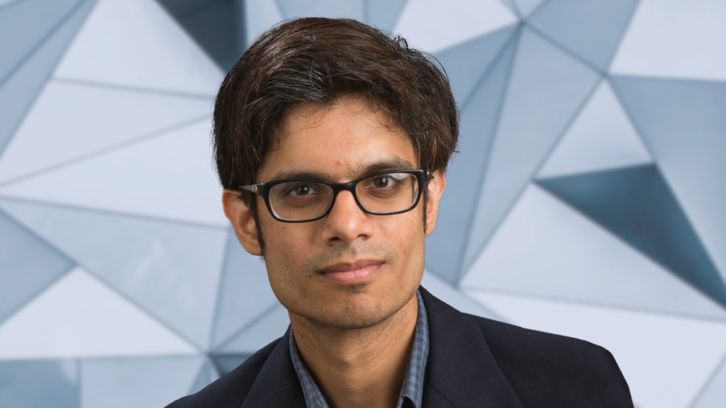 Gaurav Khanna against a bluish blurred background of geometric/triangular shapes