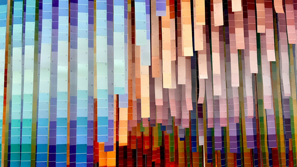 A variety of different-colored paint chips hanging in a room.